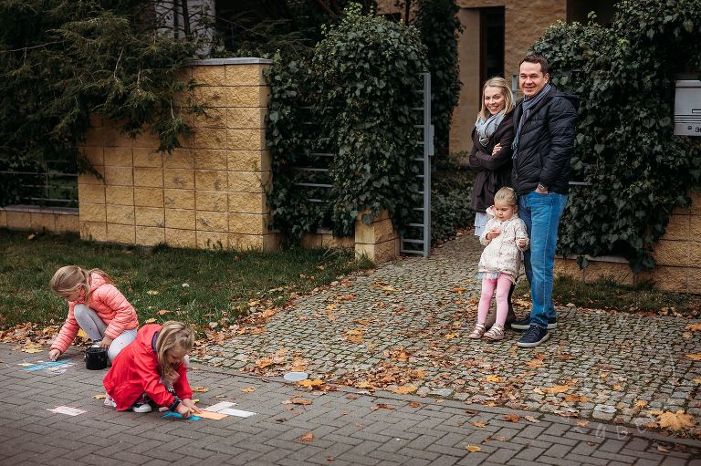 rodzice przed domem patrzą jak dzieci rysują kredą