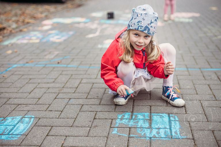 pięciolatka rysuje kredą po chodniku